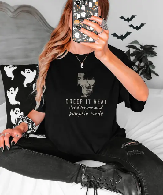 Person wearing a Black tee printed with CREEP IT REAL, DEAD LEAVES AND PUMPKIN RINDS