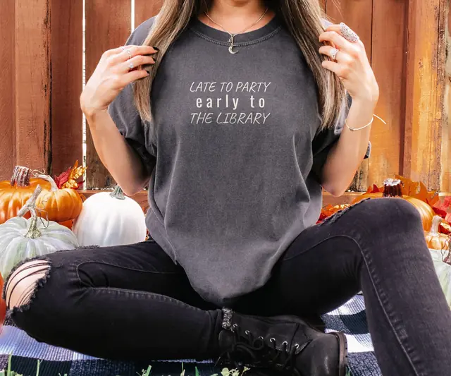 Person wearing a Pepper tee printed with LATE TO PARTY, EARLY TO, THE LIBRARY