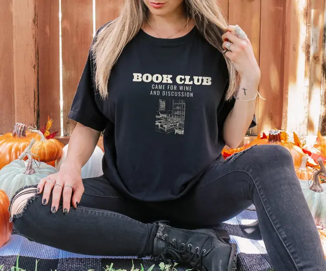 Person wearing a Black tee printed with BOOK CLUB, CAME FOR WINE AND DISCUSSION