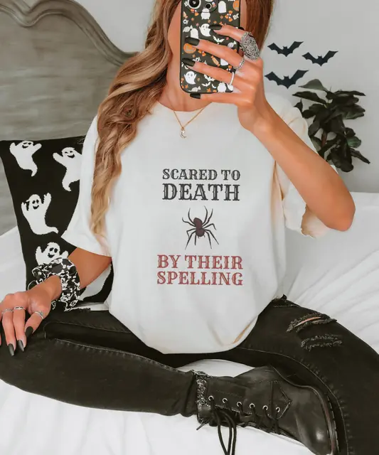 Person wearing a Ivory tee printed with SCARED TO DEATH, BY THEIR SPELLING