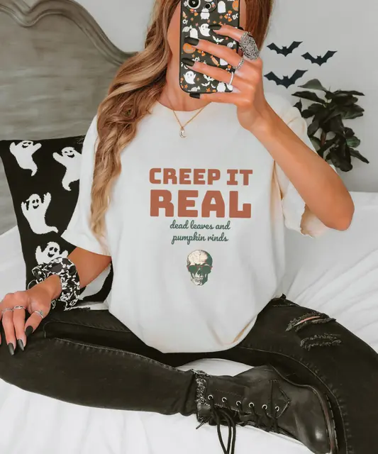 Person wearing a Ivory tee printed with CREEP IT REAL, DEAD LEAVES AND PUMPKIN RINDS