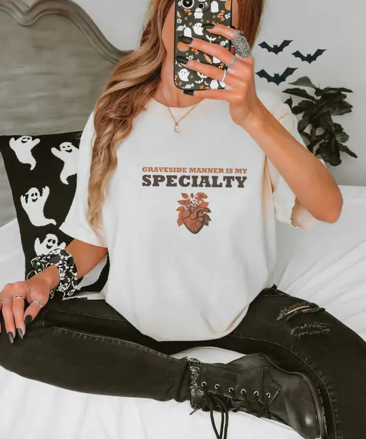 Person wearing a Ivory tee printed with GRAVESIDE MANNER, IS MY, SPECIALTY