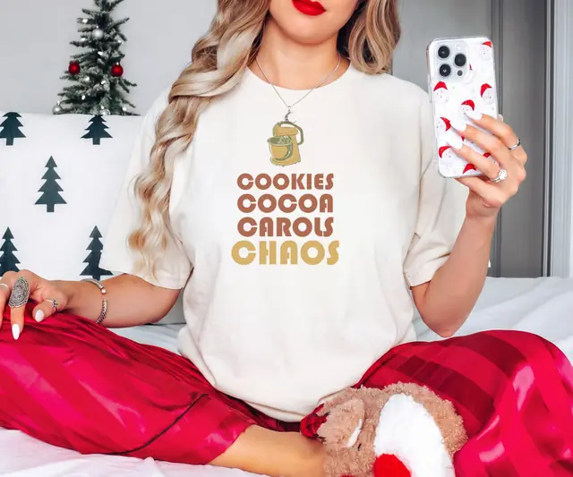 Person wearing a Ivory tee printed with COOKIES, COCOA, CAROLS, CHAOS