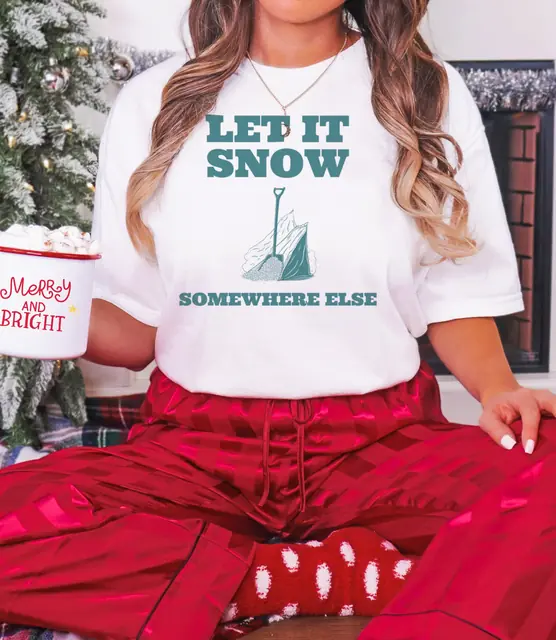 Person wearing a White tee printed with LET IT SNOW, SOMEWHERE ELSE