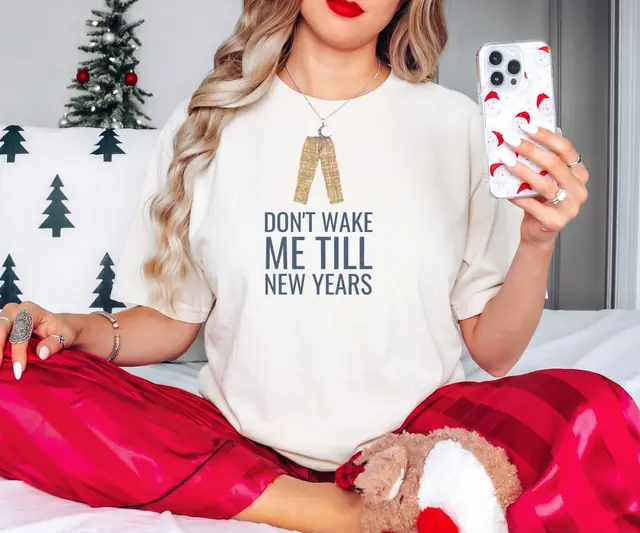 Person wearing a Ivory tee printed with DON'T WAKE ME TILL NEW YEARS